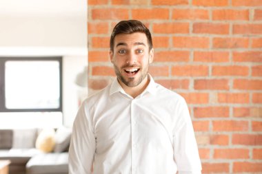 Yakışıklı iş adamı mutlu ve hoş bir şekilde şaşırmış görünüyor. Büyülenmiş ve şok olmuş bir ifadeyle heyecanlanıyor.