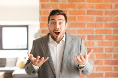 Yakışıklı iş adamı ağzı açık ve şaşırmış, şok olmuş ve hayrete düşmüş inanılmaz bir sürprizle