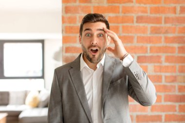 Yakışıklı iş adamı mutlu, şaşkın ve şaşırmış görünüyor, gülümsüyor ve inanılmaz ve inanılmaz iyi haberleri fark ediyor.