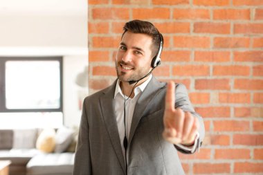 Yakışıklı pazarlamacı gururla gülümsüyor ve bir numaralı pozu başarıyla veriyor, kendini lider gibi hissediyor.