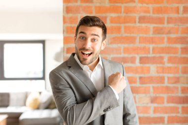 Yakışıklı iş adamı mutlu, pozitif ve başarılı hissediyor, bir meydan okumayla karşılaştığında motive oluyor veya iyi sonuçları kutluyor.