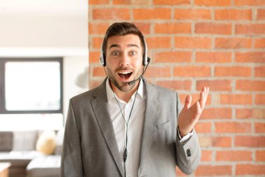 Yakışıklı pazarlamacı kendini mutlu, şaşırmış ve neşeli hisseder. Olumlu bir tavırla gülümser. Bir çözüm ya da fikri fark eder.