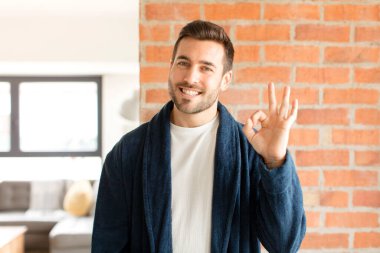 Yakışıklı adam kendini mutlu, rahat ve tatmin olmuş hissediyor. Onayını iyi bir hareketle gösteriyor. Gülümsüyor.