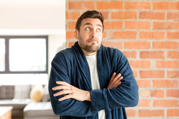 Yakışıklı adam omuz silkiyor, şaşkın ve kararsız hissediyor, kolları bağlı ve şaşkın bir şekilde şüpheye düşüyor.