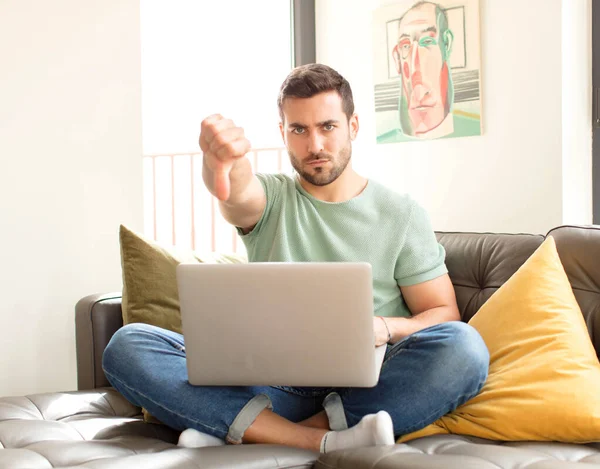 Yakışıklı bir adam kızgın, sinirli, hayal kırıklığına uğramış ya da canı sıkkın, ciddi bir bakışla başparmağını kaldırıyor.