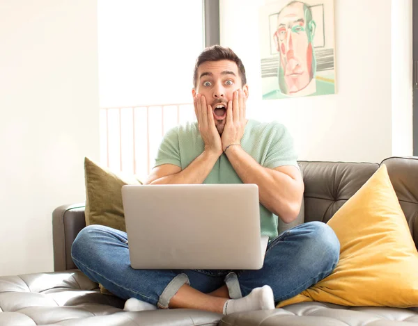 Yakışıklı adam şok olmuş ve korkmuş hissediyor, ağzı açık ve elleri yanaklarında korkmuş görünüyor.