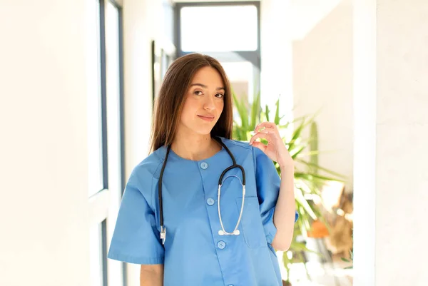 stock image pretty nurse looking arrogant, successful, positive and proud, pointing to self