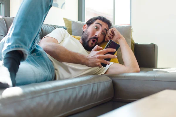 Jovem Barbudo Homem Descansando Sofá Com Seu Smartphone — Fotografia de Stock