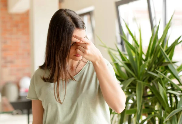 Güzel bir kadın stresli, mutsuz ve hayal kırıklığına uğramış, alnına dokunmuş ve şiddetli baş ağrısı çeken bir kadın.