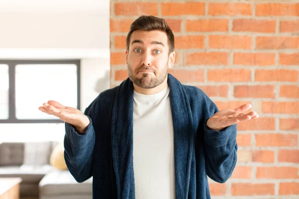 Yakışıklı adam şaşkın ve şaşkın, şüpheci, farklı seçenekleri tartıyor ya da komik bir ifadeyle seçiyor.