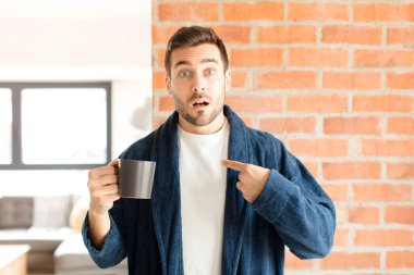 Yakışıklı adam şaşkın ve şaşkın görünüyor, ağzı açık, kendini işaret ediyor.