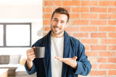 Yakışıklı bir adam neşeyle gülümsüyor, mutlu hissediyor ve fotokopi uzayda avucunun içinde bir konsept gösteriyor.