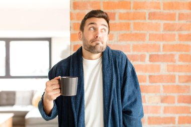 Yakışıklı adam omuz silkiyor, şaşkın ve kararsız hissediyor, kolları bağlı ve şaşkın bir şekilde şüpheye düşüyor.