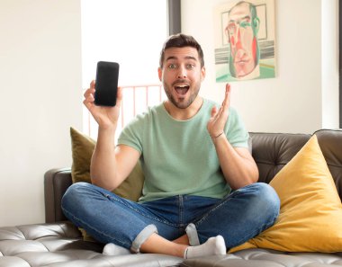 Yakışıklı adam mutlu, heyecanlı, şaşırmış ya da şaşırmış, gülümseyen ve hayrete düşmüş.