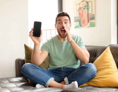 Yakışıklı adam mutlu, heyecanlı ve pozitif hissediyor. Elleri ağızda, bağırarak bağırıyor.