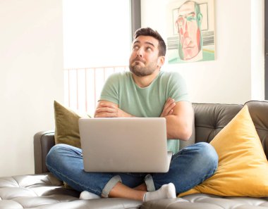 Yakışıklı adam omuz silkiyor, şaşkın ve kararsız hissediyor, kolları bağlı ve şaşkın bir şekilde şüpheye düşüyor.