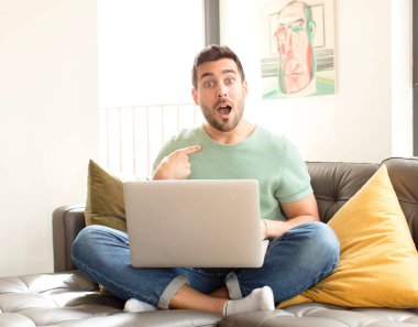 Yakışıklı adam şaşkın ve şaşkın görünüyor, ağzı açık, kendini işaret ediyor.