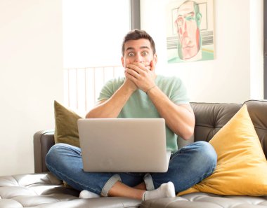 Yakışıklı bir adam elleri ile ağzını kapatıyor, şok olmuş, şaşırmış bir ifadeyle, sır saklıyor ya da 