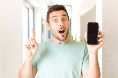 Yakışıklı bir adam bir fikri fark ettikten sonra mutlu ve heyecanlı bir dahi gibi hissediyor, neşeli bir şekilde parmağını kaldırıyor, eureka!