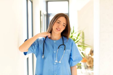 Güzel hemşire stresli, endişeli, yorgun ve hayal kırıklığına uğramış, gömleğini çekmiş, sorunlu görünüyor.