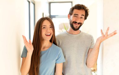 Genç çift mutlu, şaşırmış ve neşeli, pozitif bir tavırla gülümsüyor, bir çözüm ya da fikrin farkına varıyor.