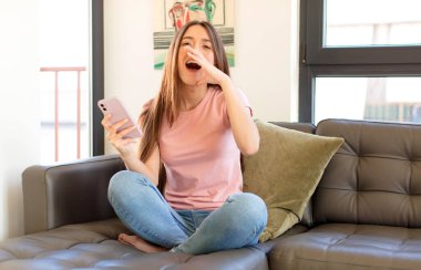 Güzel bir kadın mutlu, heyecanlı ve pozitif hissediyor. Elleri ağızda, bağırıyor.