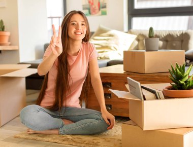 Güzel bir kadın gülümsüyor ve arkadaş canlısı görünüyor. İki ya da iki numarayı gösteriyor. Elleri önde, geri sayıyor.