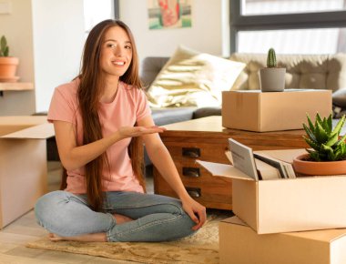 Güzel bir kadın neşeyle gülümsüyor, mutlu hissediyor ve bir konsepti fotokopi uzayında el ele vererek gösteriyor.