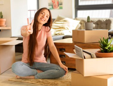 Güzel bir kadın gülümsüyor ve mutlu görünüyor, kaygısız ve pozitif, işaret eden zafer ya da barış tek elle