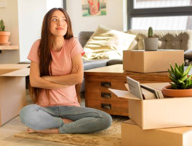 Güzel bir kadın omuz silkiyor, şaşkın ve kararsız hissediyor, kolları bağlı ve şaşkın bir şekilde şüpheye düşüyor.