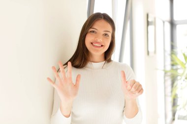 Güzel bir kadın gülümsüyor ve arkadaş canlısı görünüyor, altı ya da altıncı numarayı gösteriyor, eli önde, geriye doğru sayıyor.