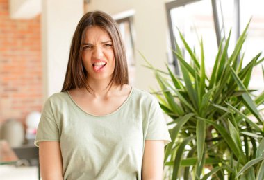 Güzel bir kadın tiksinmiş ve rahatsız olmuş hissediyor, dilini dışarı çıkarıyor, iğrenç ve iğrenç bir şeyden hoşlanmıyor.