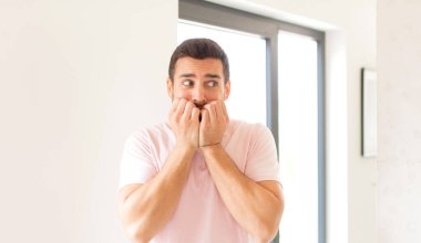 Yakışıklı adam endişeli, gergin, stresli ve korkmuş görünüyor tırnaklarını yiyor ve yanal fotokopi için yer arıyor.