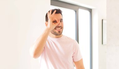 Yakışıklı adam mutlu bir şekilde gülümsüyor, şaka yapıyor, gözetleme deliğinden bakıyor, sırları gözetliyor.