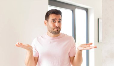 Yakışıklı adam şaşkın ve şaşkın, şüpheci, farklı seçenekleri tartıyor ya da komik bir ifadeyle seçiyor.