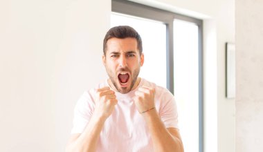 Yakışıklı adam sinirli, sinirli, sinirli bakışlar ve yumruklar ile agresif bir şekilde bağırıyor.