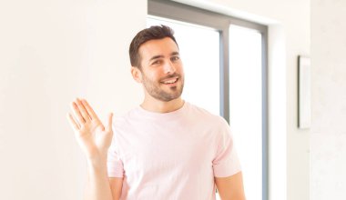 Yakışıklı adam mutlu ve neşeyle gülümsüyor, el sallıyor, seni selamlıyor ya da hoşça kal diyor.