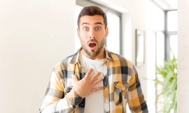 Yakışıklı adam şaşkın, şaşkın ve şaşırmış hissediyor, elleri göğsünde ve ağzı açık, kim olduğunu söylüyor, ben mi??