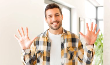 Yakışıklı bir adam gülümsüyor ve arkadaş canlısı görünüyor, onuncu ya da onuncu numarayı gösteriyor, eli önde, geri sayıyor.