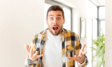 Yakışıklı, ağzı açık ve şaşırmış, şok olmuş ve hayrete düşmüş bir adam.
