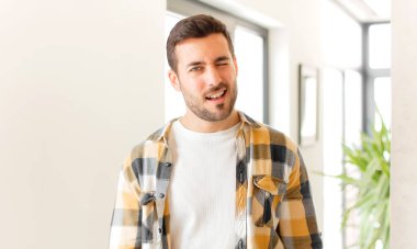 Yakışıklı adam mutlu ve arkadaş canlısı görünüyor, gülümsüyor ve sana olumlu bir tavırla göz kırpıyor.