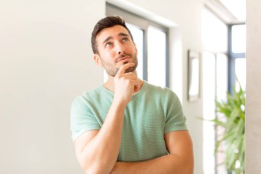 Yakışıklı bir adam düşünceli, meraklı ya da hayal kuruyor, hayal kuruyor ve uzayı kopyalamak için yukarı bakıyor.