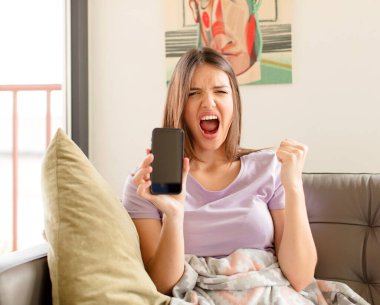 Güzel bir kadın öfkeli bir ifadeyle ya da yumruklarıyla başarıyı kutlarken agresif bir şekilde bağırıyor.