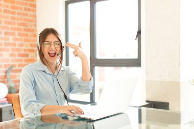 Oldukça tele pazarlamacı mutsuz ve stresli görünüyor, intihar jesti elle silah işareti yapıyor, kafasını işaret ediyor.