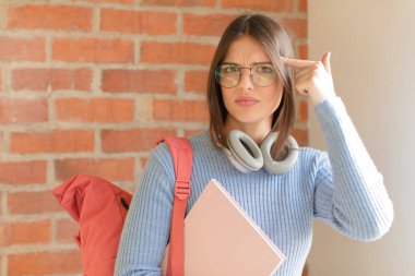 Güzel öğrenci kafası karışık ve şaşkın hissediyor. Deli, deli ya da aklını kaçırmış olduğunu gösteriyor.