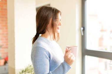 Profil görünümündeki güzel kadın ileriyi kopyalamak istiyor, düşünüyor, hayal ediyor ya da hayal kuruyor.