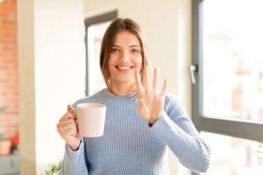 Güzel bir kadın gülümsüyor ve arkadaş canlısı görünüyor, dört ya da dört numarayı gösteriyor, eli önde, geriye doğru sayıyor.