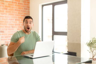 Yakışıklı adam şaşkın ve şaşkın görünüyor, ağzı açık, kendini işaret ediyor.