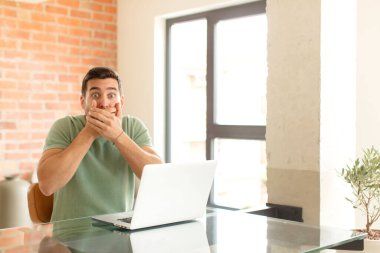 Yakışıklı bir adam elleri ile ağzını kapatıyor, şok olmuş, şaşırmış bir ifadeyle, sır saklıyor ya da 