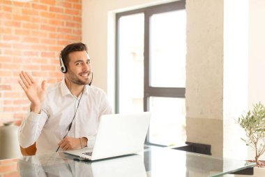 Yakışıklı pazarlamacı mutlu ve neşeli bir şekilde gülümsüyor, el sallıyor, seni selamlıyor, ya da hoşça kal diyor.